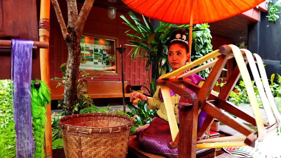 Jim Thompson House. A girl spins silk in Bangkok